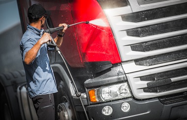 front of tractor trailer getting hand washed with water sprayer