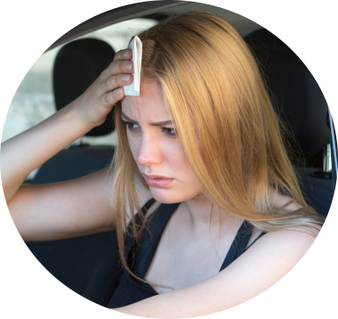 woman wiping sweat from her forehead sitting inside a car with the window rolled down