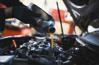 mechanic performing automotive maintenance by changing adding new fluid
